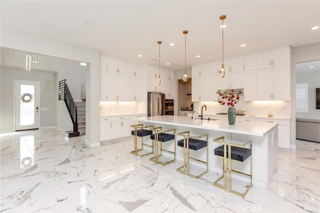 kitchen featuring appliances with stainless steel finishes, a breakfast bar, a spacious island, decorative light fixtures, and white cabinets