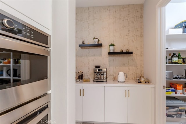 bar with white cabinets and stainless steel double oven