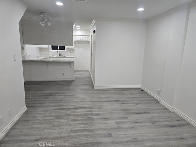 kitchen with a breakfast bar, kitchen peninsula, sink, crown molding, and white cabinetry