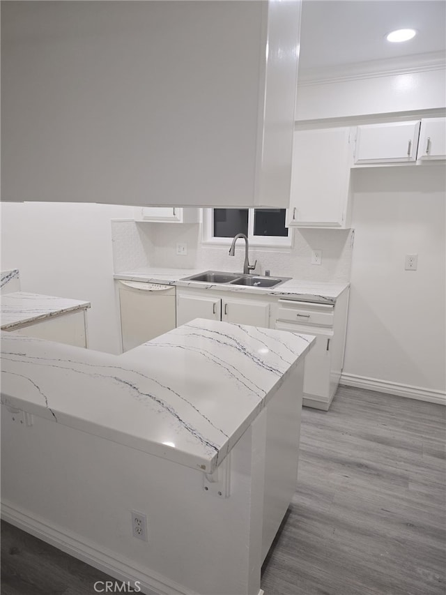 kitchen featuring white cabinets, dishwasher, light hardwood / wood-style floors, sink, and light stone counters