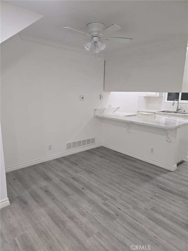 interior space featuring ceiling fan, sink, crown molding, and light hardwood / wood-style floors