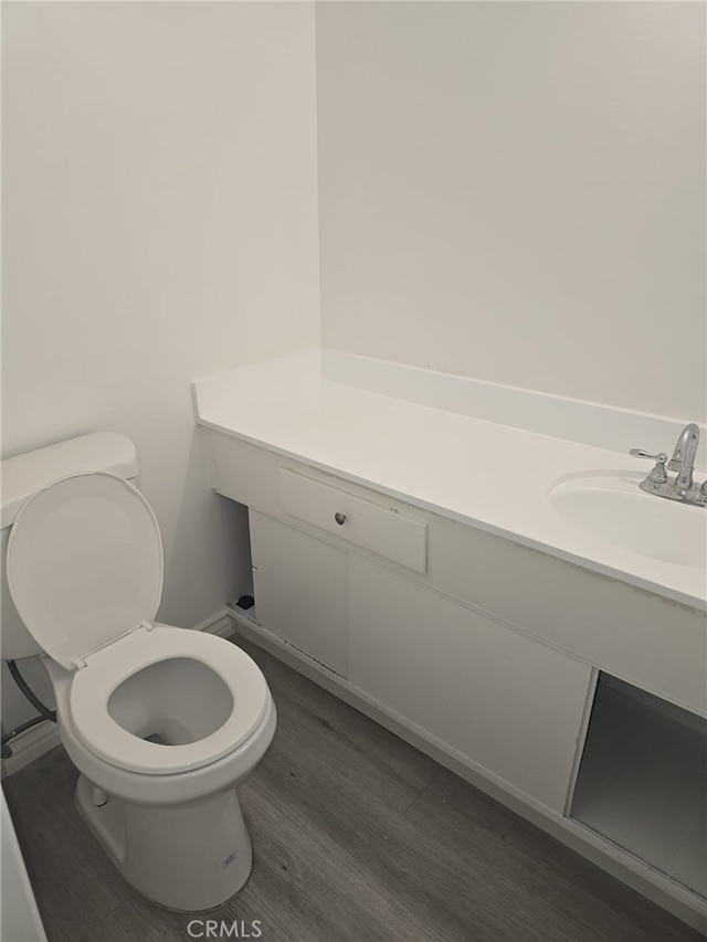 bathroom with toilet, vanity, and hardwood / wood-style flooring