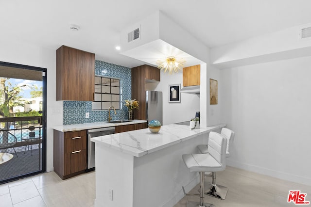 kitchen featuring sink, stainless steel appliances, tasteful backsplash, kitchen peninsula, and a breakfast bar