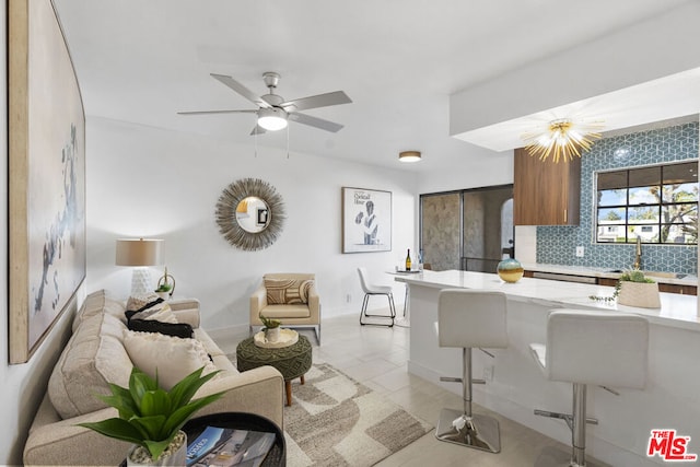 kitchen with a breakfast bar, backsplash, sink, light tile patterned floors, and kitchen peninsula