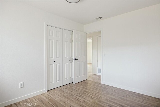 unfurnished bedroom with light wood-type flooring and a closet