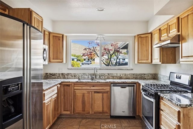 kitchen featuring dark tile patterned floors, light stone countertops, sink, and stainless steel appliances