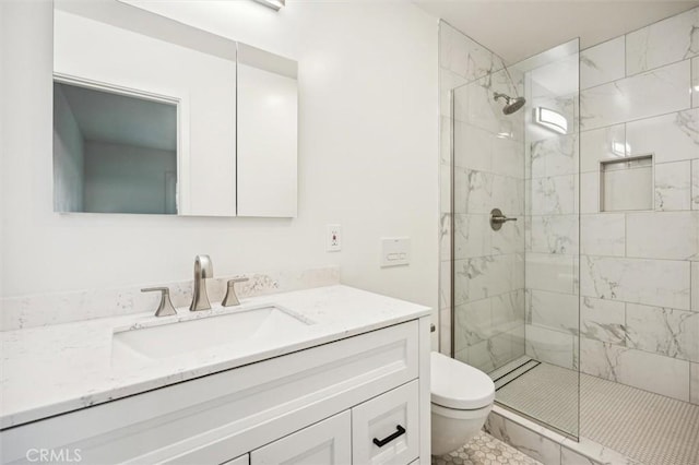 bathroom featuring toilet, vanity, and a tile shower