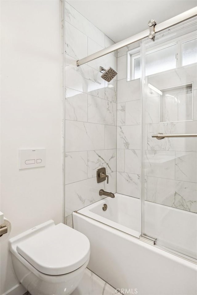 bathroom featuring toilet and bath / shower combo with glass door