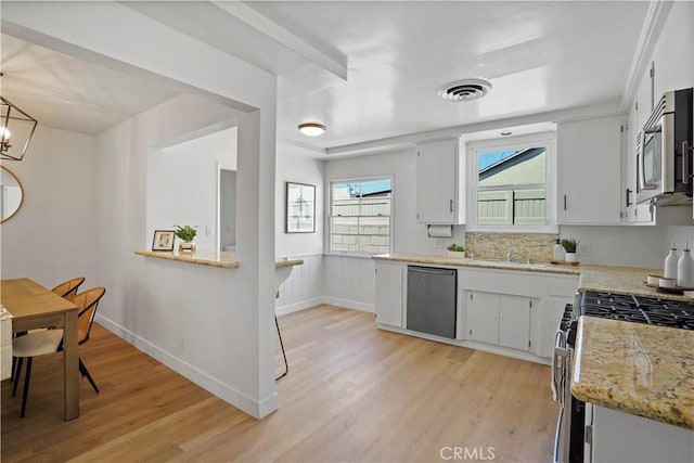 kitchen featuring white cabinetry, appliances with stainless steel finishes, light hardwood / wood-style flooring, and an inviting chandelier