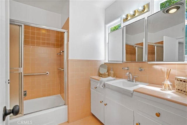 bathroom featuring tile walls, enclosed tub / shower combo, and vanity