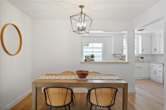 dining room with light wood-type flooring and an inviting chandelier