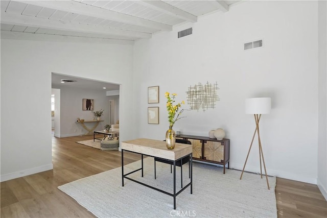 office area featuring a towering ceiling, wood ceiling, beam ceiling, and wood-type flooring