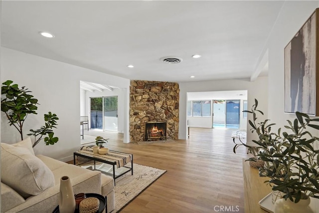 living room with a fireplace, beamed ceiling, and light hardwood / wood-style floors