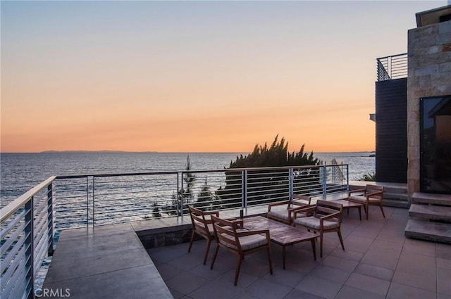 patio terrace at dusk with a balcony and a water view