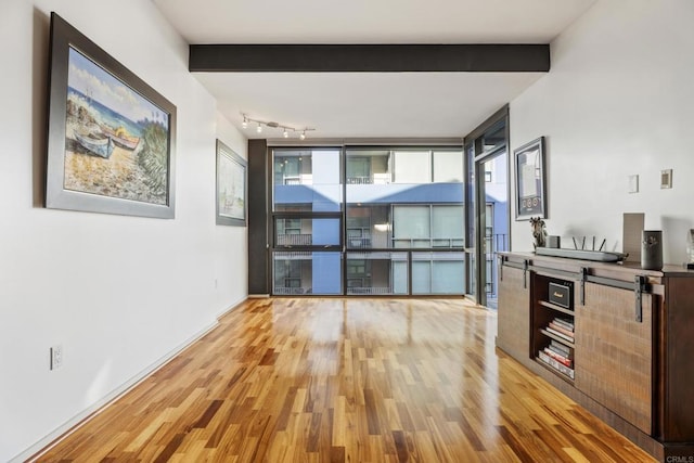 interior space featuring beamed ceiling and light hardwood / wood-style floors