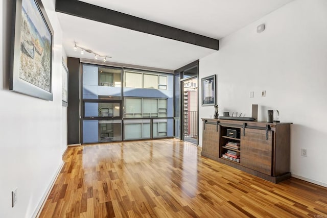 unfurnished living room featuring beamed ceiling and light hardwood / wood-style floors