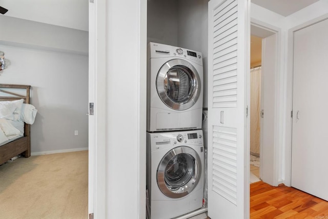 washroom featuring light hardwood / wood-style flooring and stacked washer and clothes dryer