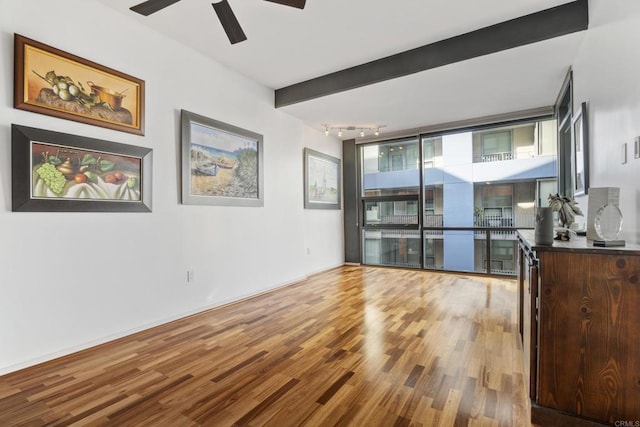 living room featuring ceiling fan, beam ceiling, wood-type flooring, and a wealth of natural light