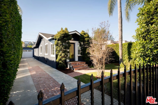 view of property hidden behind natural elements with an outdoor structure and a garage