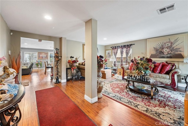 living room featuring baseboards, plenty of natural light, visible vents, and light wood-style floors