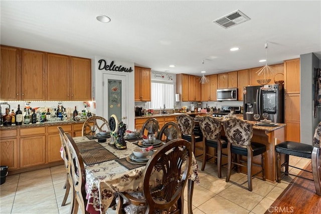 kitchen featuring light stone counters, light tile patterned flooring, a kitchen island, and stainless steel appliances