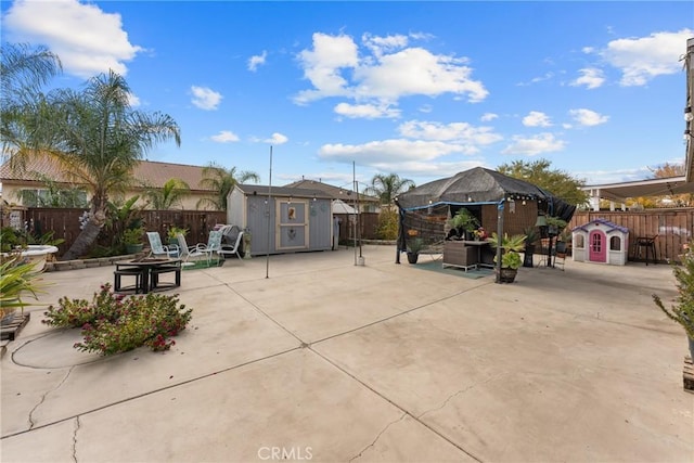 view of patio / terrace featuring a gazebo, an outbuilding, a fenced backyard, and a storage shed