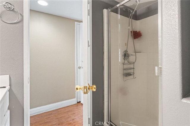 full bathroom featuring a shower stall, baseboards, wood finished floors, and vanity