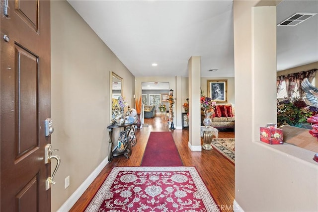 foyer entrance featuring dark wood-style flooring, visible vents, and baseboards