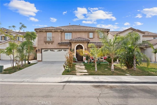 mediterranean / spanish-style home with a garage, concrete driveway, a tile roof, and stucco siding