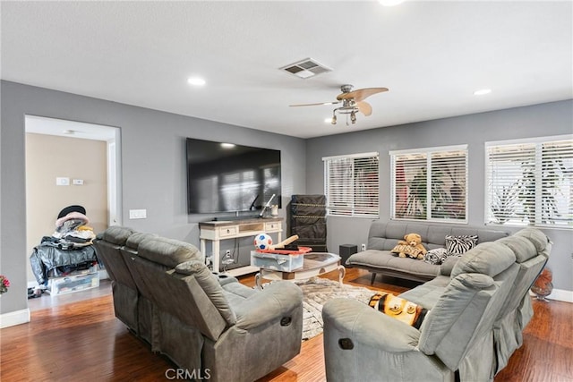 living area with a ceiling fan, visible vents, dark wood finished floors, and baseboards