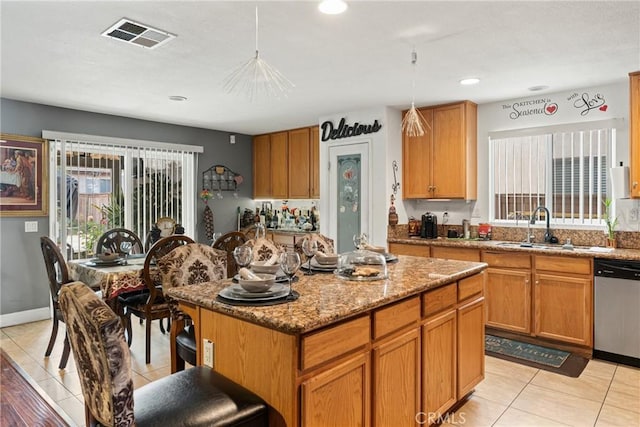 kitchen featuring light stone counters, stainless steel dishwasher, sink, a kitchen island, and hanging light fixtures