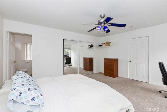 carpeted bedroom featuring a closet, ceiling fan, and ensuite bathroom