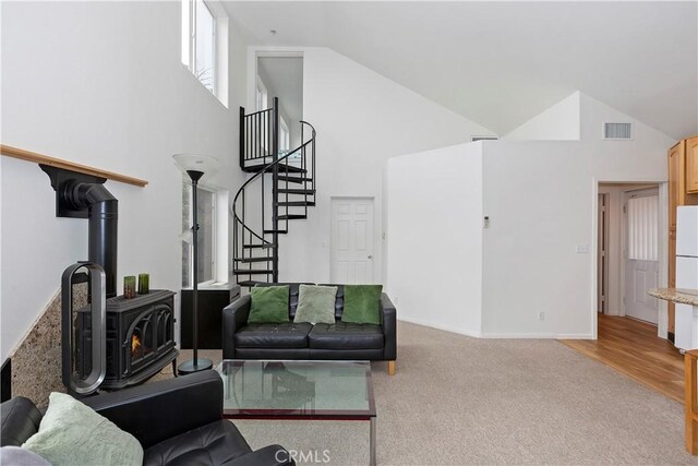 living room featuring light hardwood / wood-style floors, a wood stove, and high vaulted ceiling