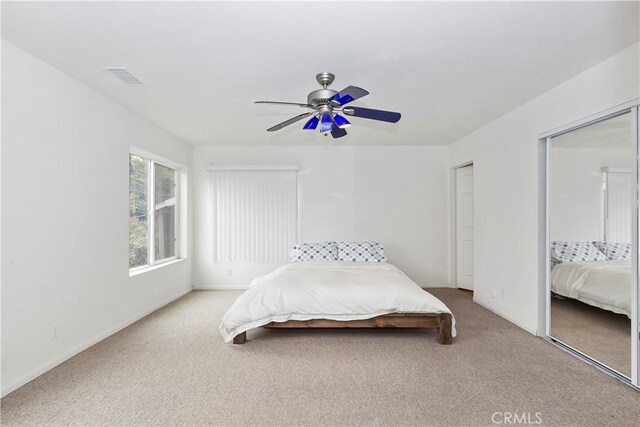 bedroom featuring light carpet, two closets, and ceiling fan