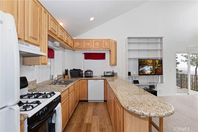 kitchen with kitchen peninsula, light hardwood / wood-style floors, white appliances, a breakfast bar area, and light brown cabinetry