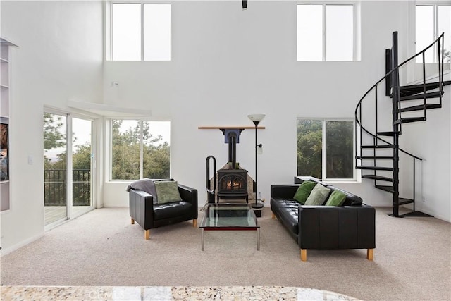 living room with carpet flooring, a wood stove, and a towering ceiling