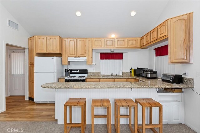 kitchen featuring lofted ceiling, white appliances, sink, a kitchen bar, and kitchen peninsula