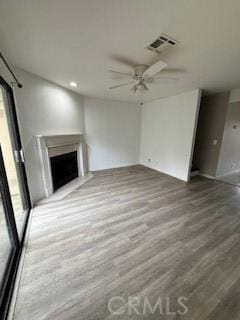 unfurnished living room featuring ceiling fan, plenty of natural light, and wood-type flooring