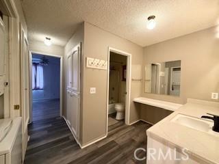 full bathroom featuring vanity, a textured ceiling, wood-type flooring, washtub / shower combination, and toilet