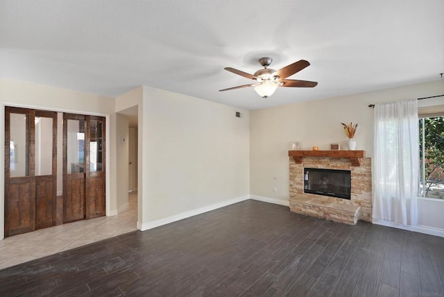 unfurnished living room with a stone fireplace, ceiling fan, and hardwood / wood-style floors