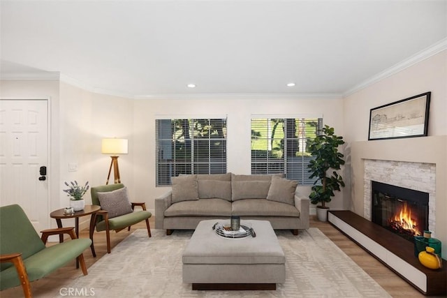 living room featuring light wood-type flooring, a stone fireplace, and ornamental molding