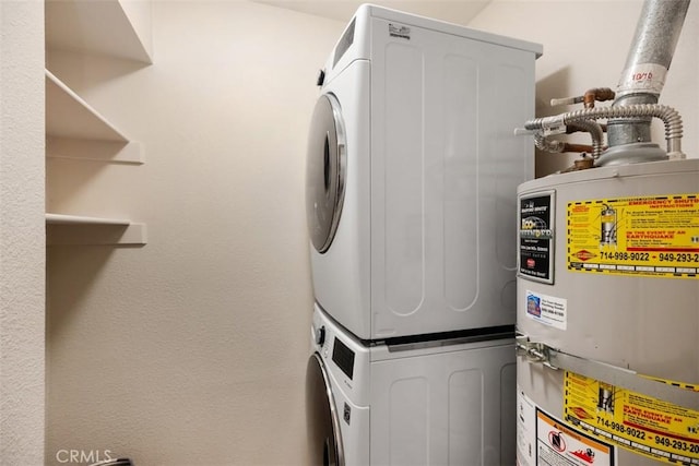 clothes washing area with gas water heater and stacked washing maching and dryer