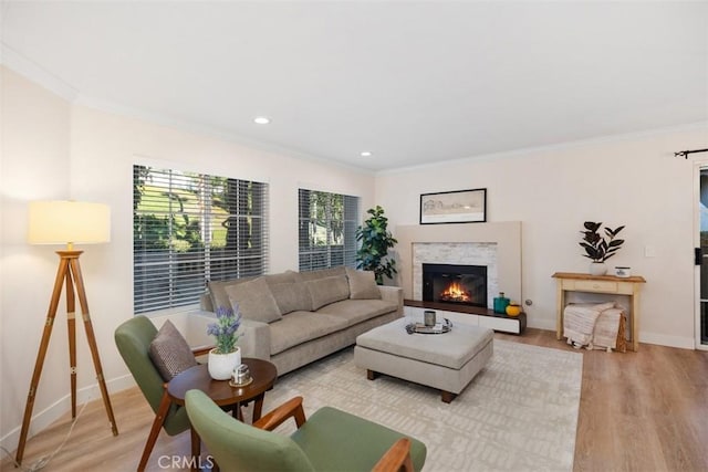 living room featuring light wood-type flooring, ornamental molding, and a tile fireplace