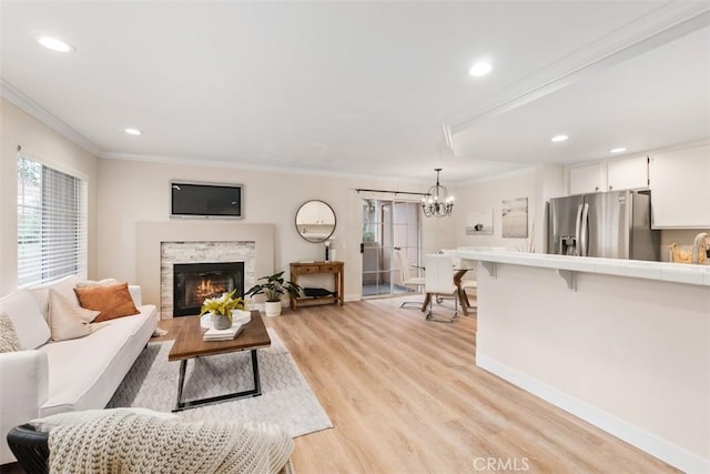 living room featuring light wood-type flooring, a notable chandelier, and ornamental molding