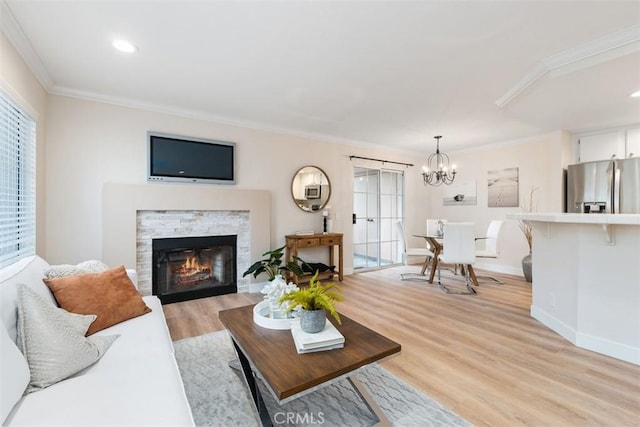 living room featuring a chandelier, light hardwood / wood-style flooring, ornamental molding, and a fireplace