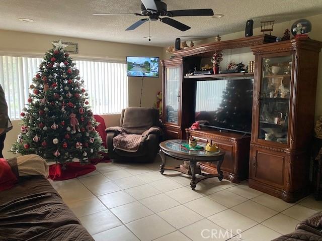 tiled living room featuring ceiling fan and a textured ceiling