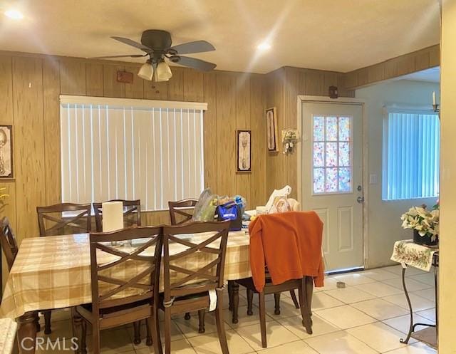 tiled dining space with wood walls and ceiling fan