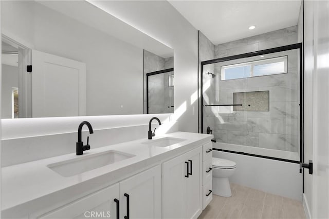 full bathroom featuring tile patterned floors, vanity, toilet, and bath / shower combo with glass door