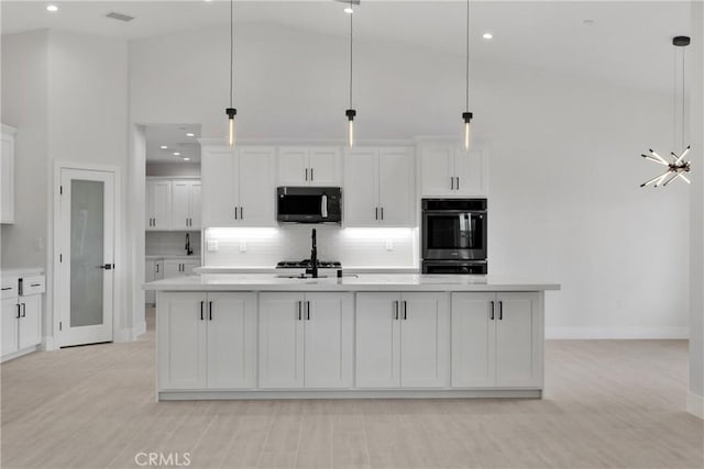 kitchen featuring pendant lighting, high vaulted ceiling, stainless steel appliances, and a kitchen island with sink