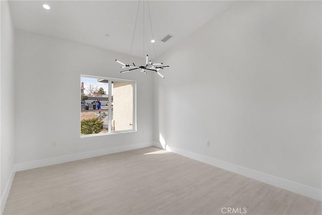 spare room featuring light hardwood / wood-style flooring and an inviting chandelier